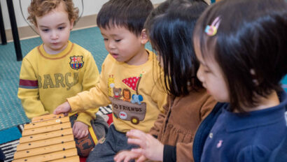 Group of toddlers playing with a xylophone.