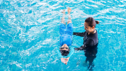 Instructor helping a student float on their back in the pool.