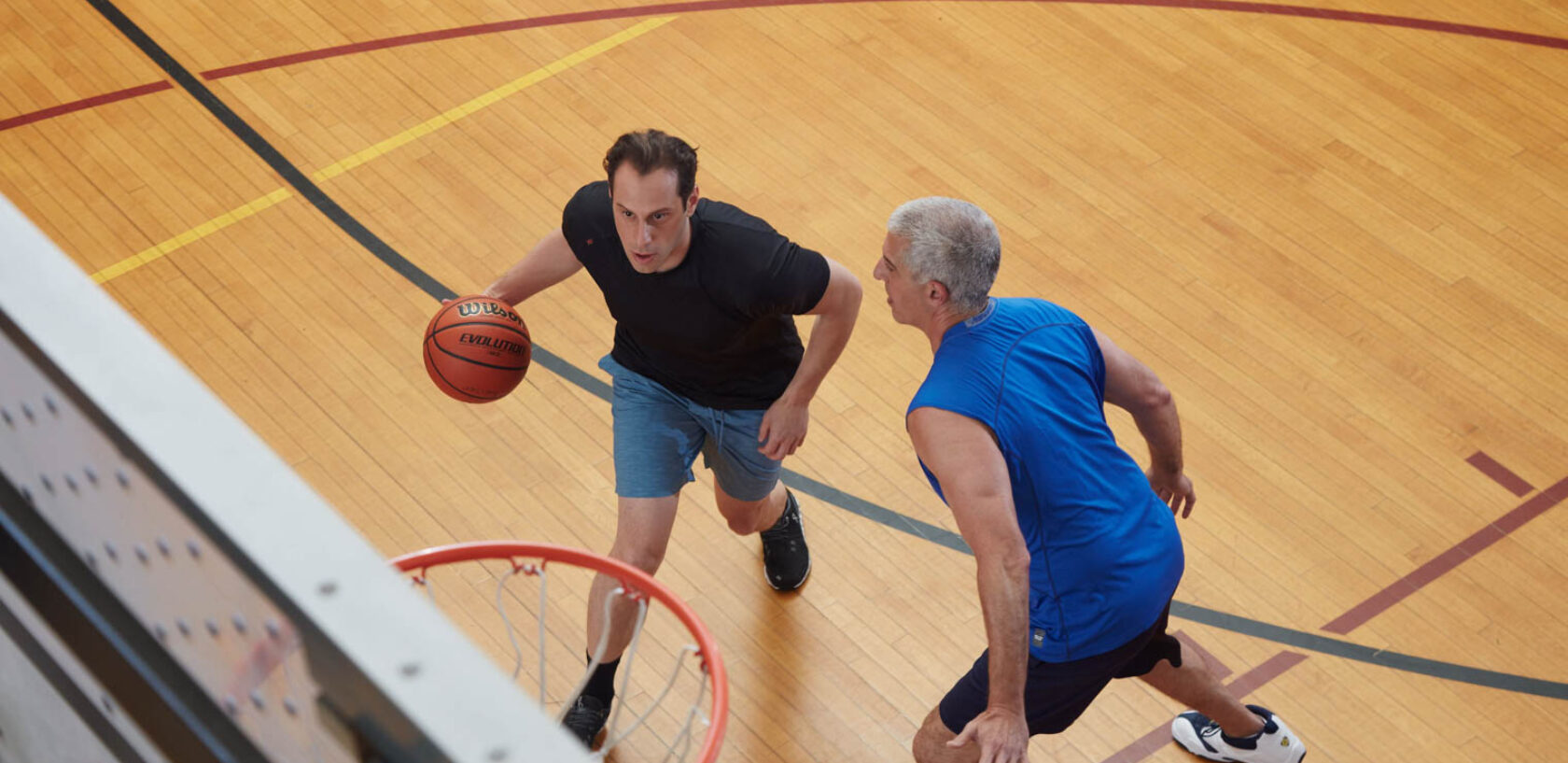 Two adult men playing basketball.