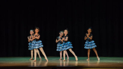 Dance performance on stage with blue skirts.