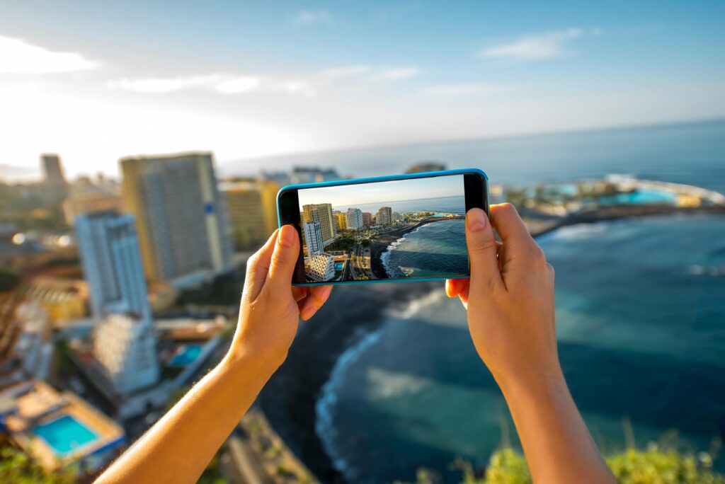 women holding phone taking a picture of a view.