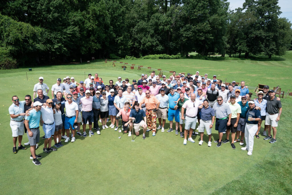 Large group photo on a golf course green.