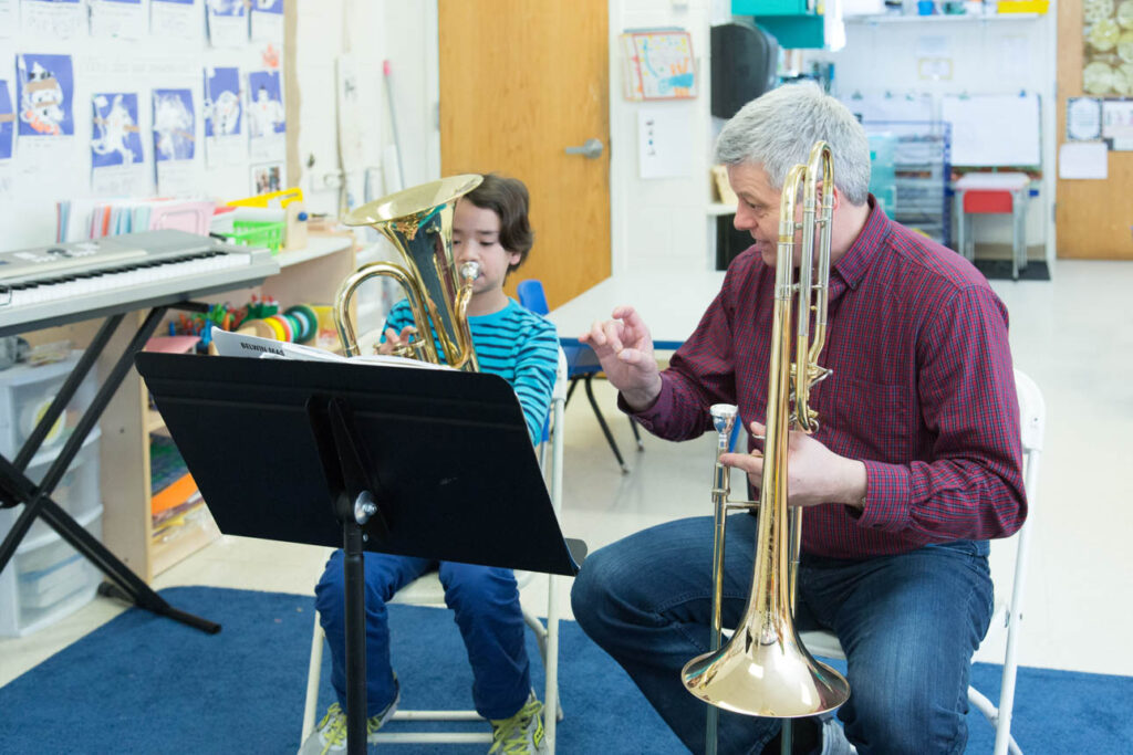 Teacher giving a horn lesson to a young boy.