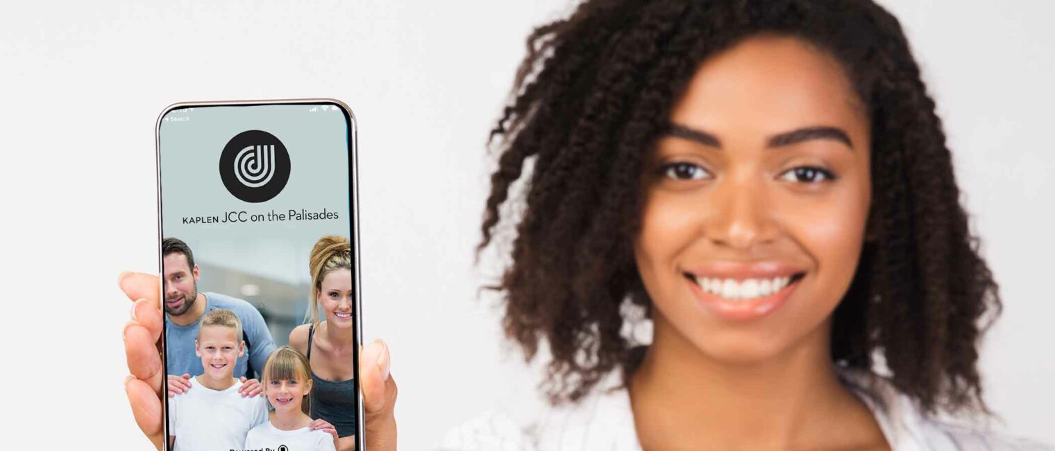 Women holding an iphone with the KJCC app.