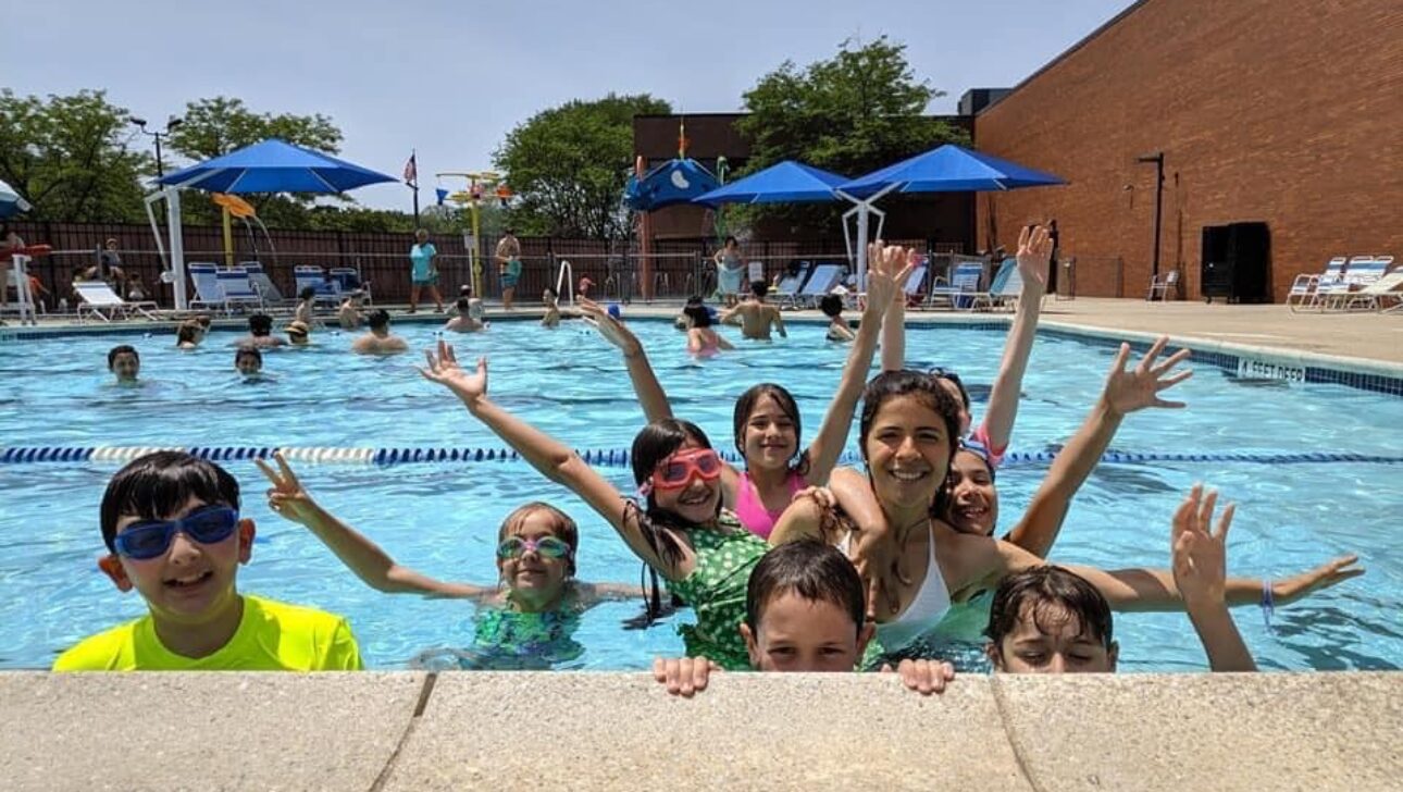 Children smiling doing group activities in the pool.