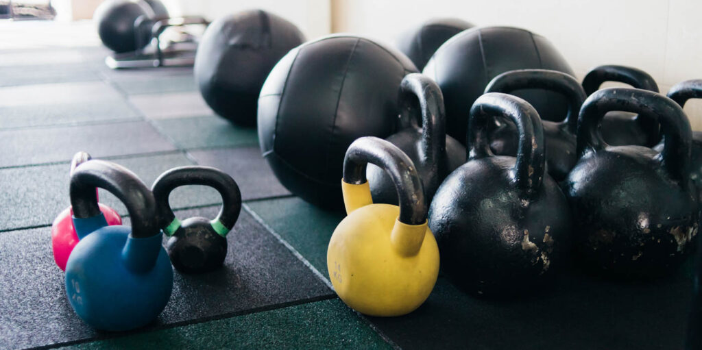 Kettlebells and medicine balls lined up on the floor.