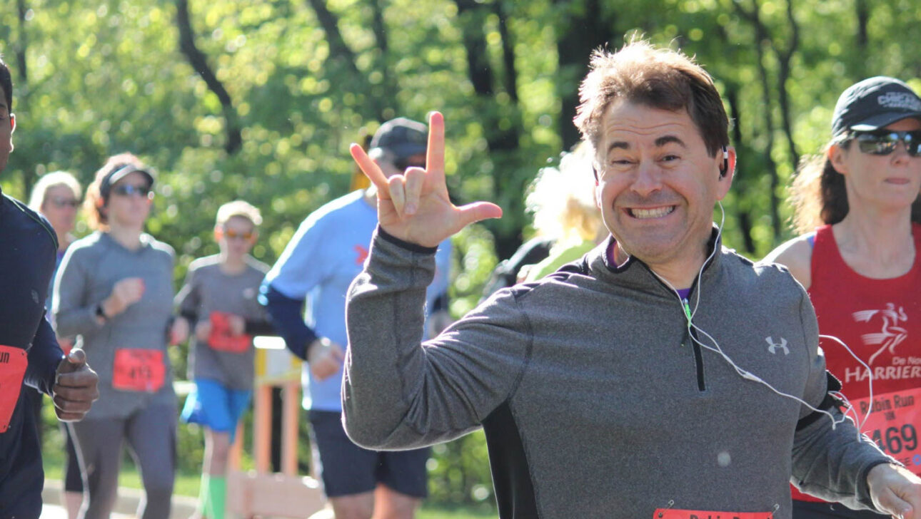 Man running the race giving the love sign language symbol.