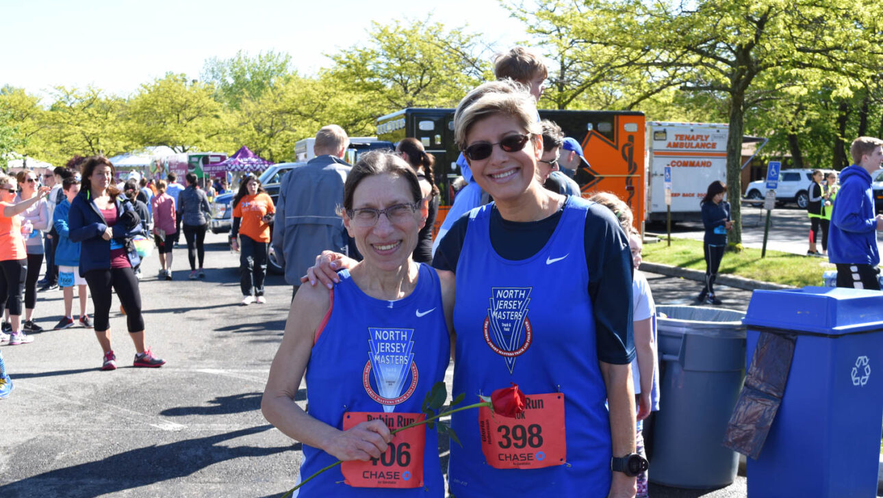Two ladies in blue Rubin Run shirts holding a rose.