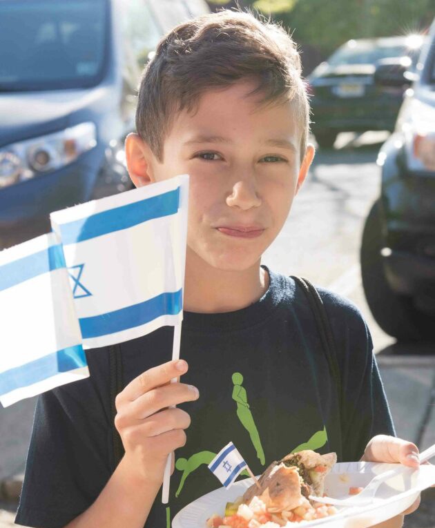 Boy holding plate and Israeli flag.