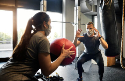 Woman throwing a medicine ball to a man in the gym.