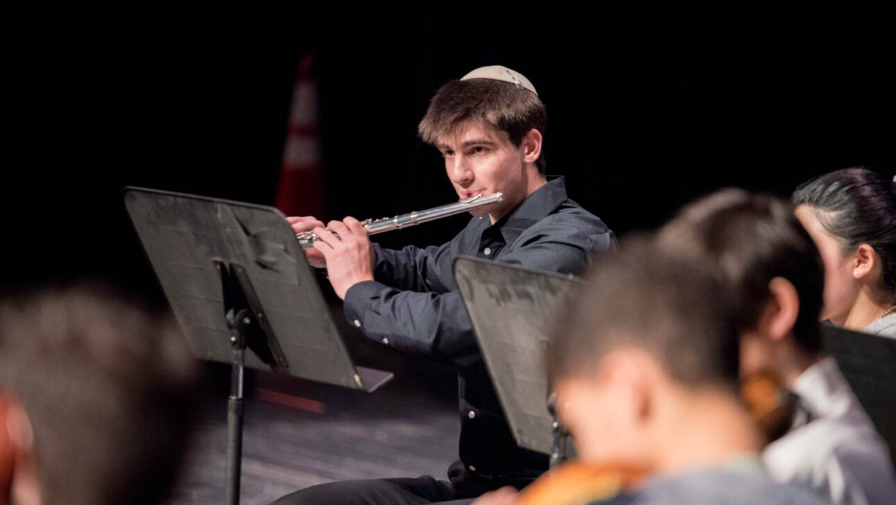 Teen boy playing the flute on stage.