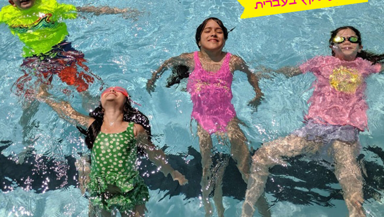 Group shot of children smiling and swimming in a pool.