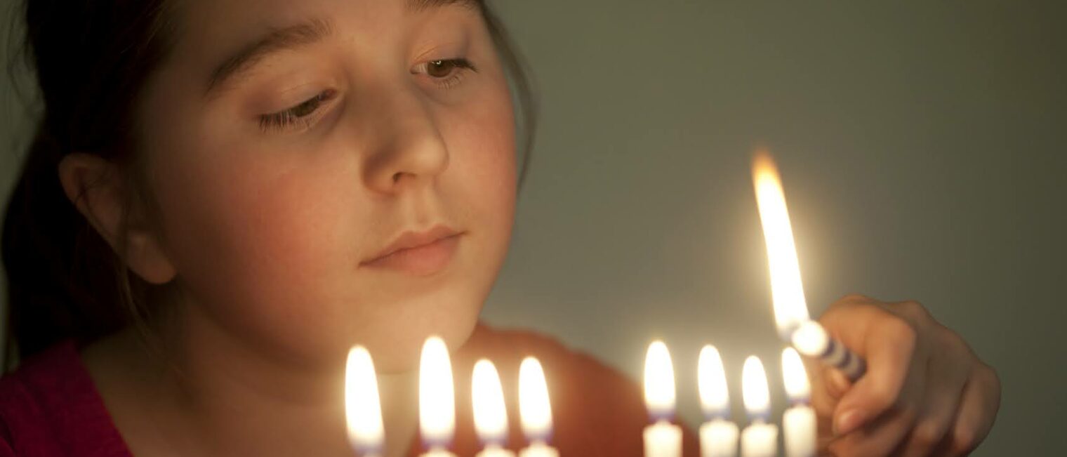 Girl, age 11, lights a menorah.