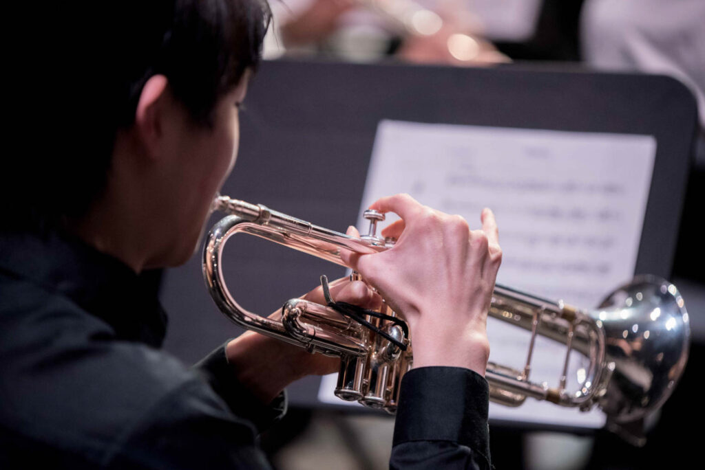 Teen boy playing the trumpet on stage.