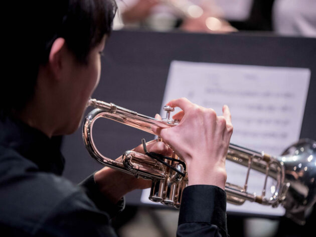 Teen boy playing the trumpet on stage.
