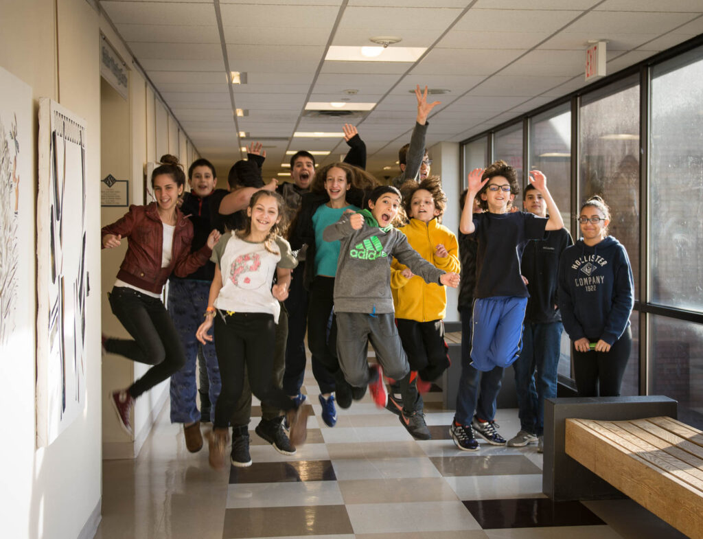 Group of teens jumping in the air in the hallway.